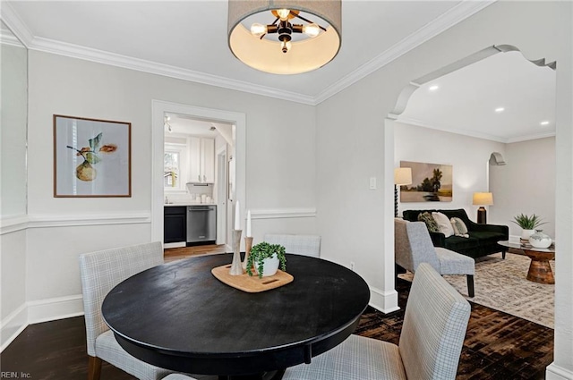 dining area with baseboards, wood finished floors, arched walkways, and ornamental molding