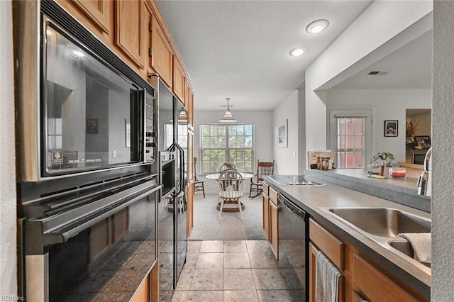 kitchen featuring visible vents, light colored carpet, brown cabinets, black appliances, and a sink