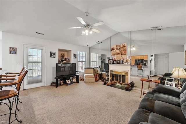 carpeted living area featuring visible vents, a healthy amount of sunlight, a ceiling fan, and vaulted ceiling