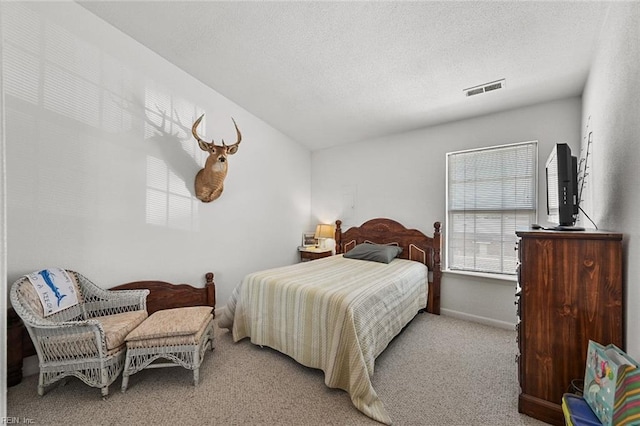 bedroom featuring visible vents, carpet flooring, a textured ceiling, and baseboards