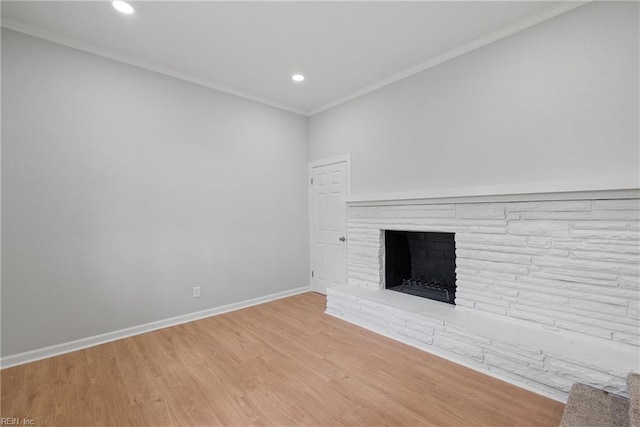 unfurnished living room featuring baseboards, recessed lighting, a fireplace with raised hearth, ornamental molding, and light wood-type flooring