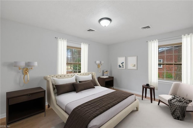 bedroom featuring visible vents, baseboards, and wood finished floors