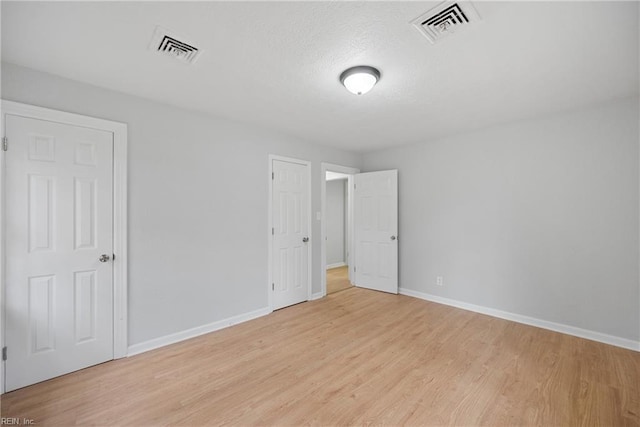 unfurnished bedroom featuring visible vents, light wood-style flooring, and baseboards