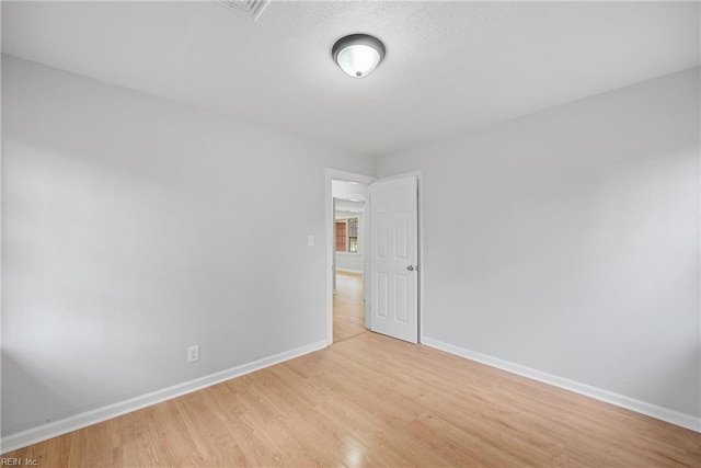 unfurnished room featuring baseboards, a textured ceiling, and light wood finished floors