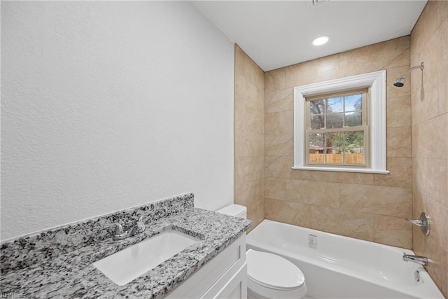 full bath with vanity, toilet, a textured wall, and shower / washtub combination