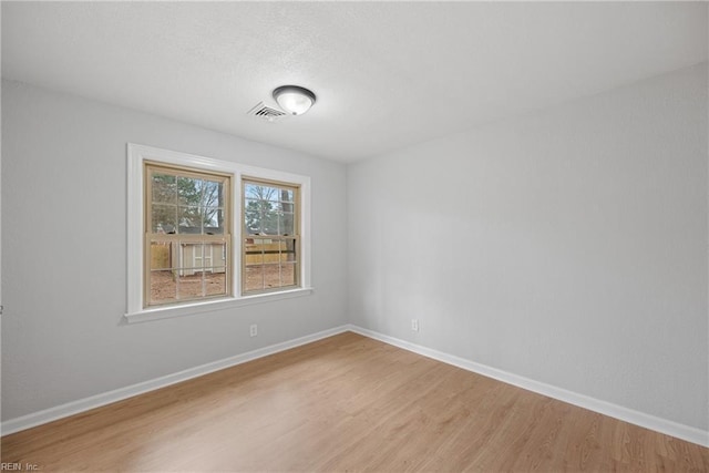 unfurnished room featuring visible vents, baseboards, and light wood-style floors