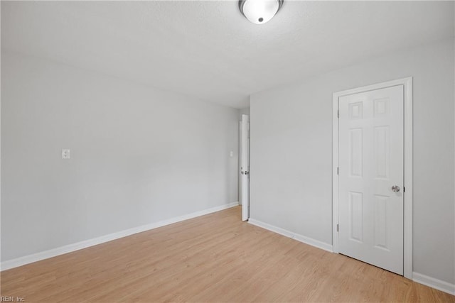 spare room featuring baseboards and light wood-style flooring