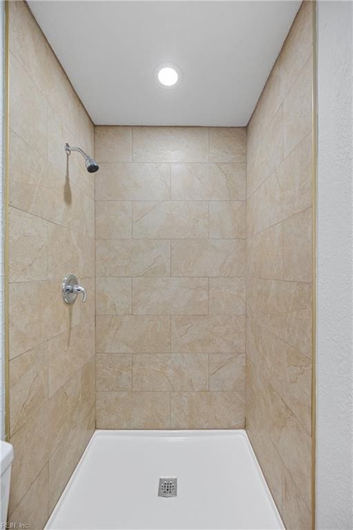 bathroom with toilet and a tile shower