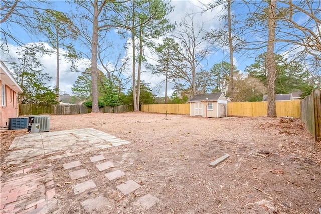 view of yard with central air condition unit, an outbuilding, a patio, a fenced backyard, and a storage shed