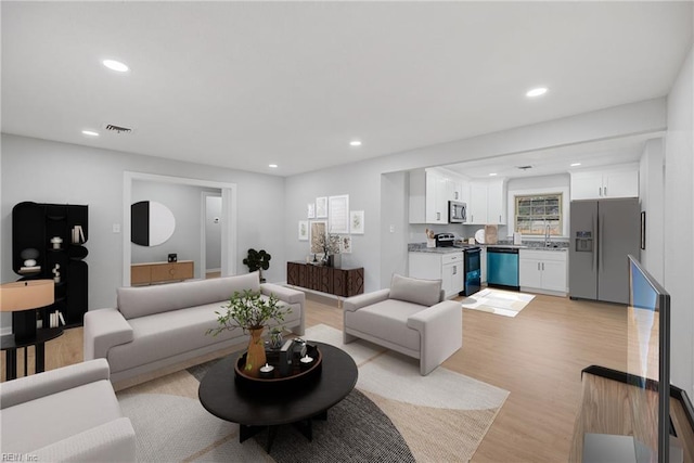 living room with recessed lighting, visible vents, and light wood-style floors