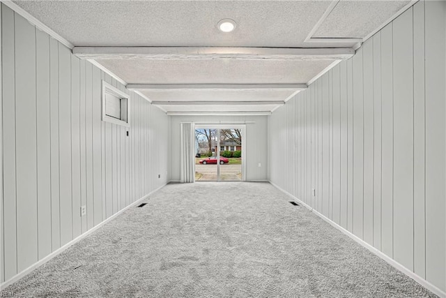 spare room with beamed ceiling, baseboards, carpet, and a textured ceiling