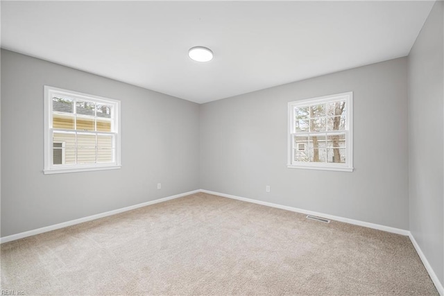 carpeted spare room with visible vents and baseboards