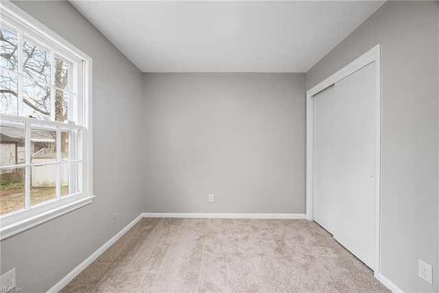 unfurnished bedroom with multiple windows, carpet, a closet, and baseboards