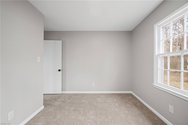 carpeted empty room with a wealth of natural light and baseboards