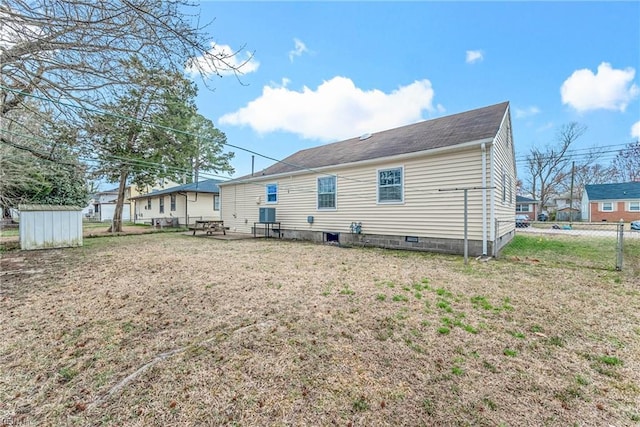 rear view of property with an outbuilding, a shed, a lawn, and fence