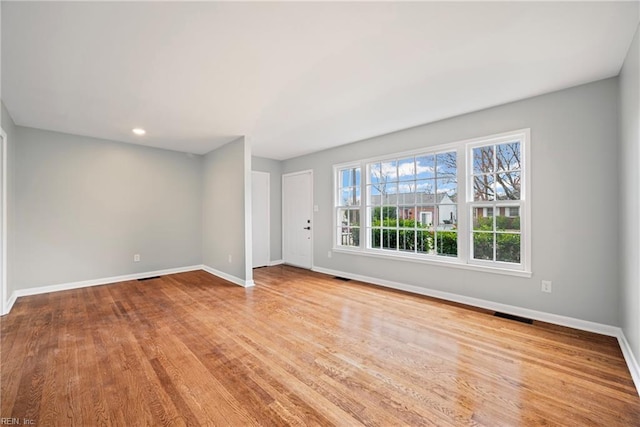 spare room with visible vents, baseboards, and wood finished floors