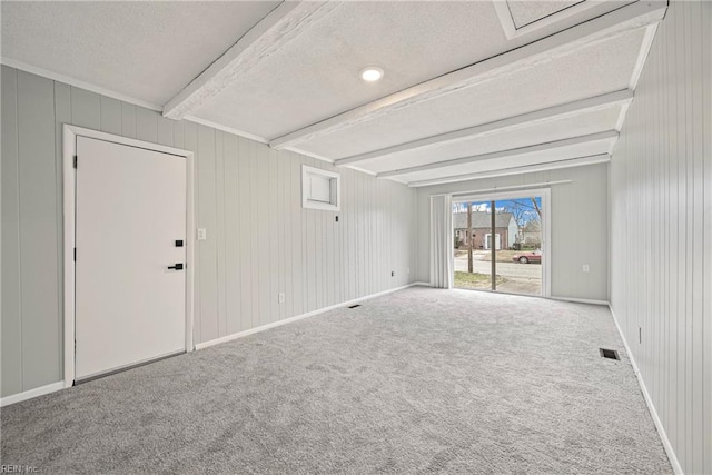 spare room featuring beamed ceiling, baseboards, carpet, and visible vents