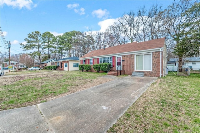 view of front of home featuring driveway, brick siding, a front lawn, and entry steps