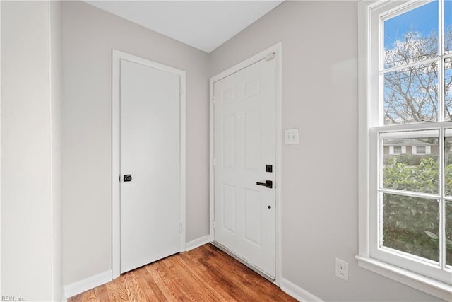 doorway featuring light wood finished floors and baseboards