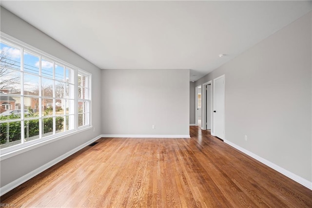 empty room featuring visible vents, baseboards, and wood finished floors