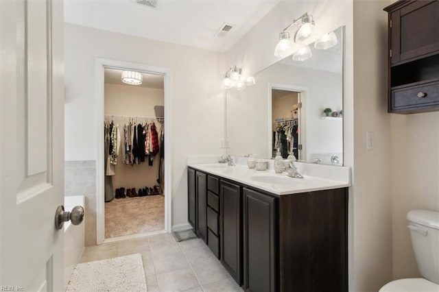 full bath with visible vents, double vanity, a sink, tile patterned floors, and toilet