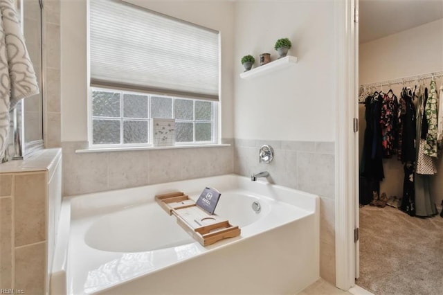 full bath featuring a walk in closet and a garden tub