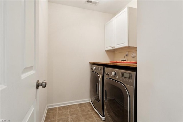 clothes washing area with washing machine and clothes dryer, visible vents, cabinet space, and baseboards