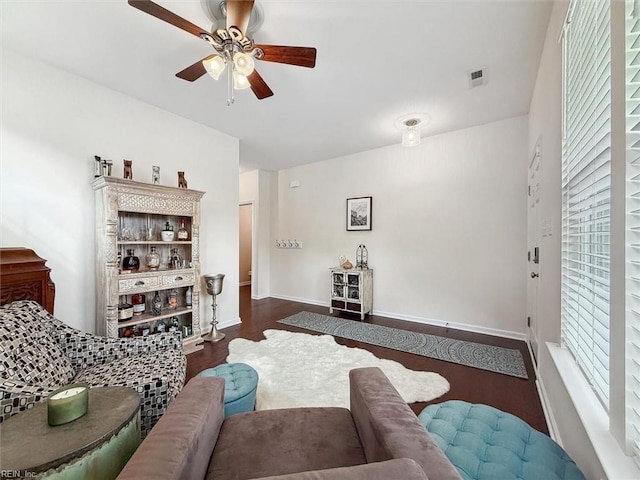 living room featuring visible vents, wood finished floors, baseboards, and ceiling fan