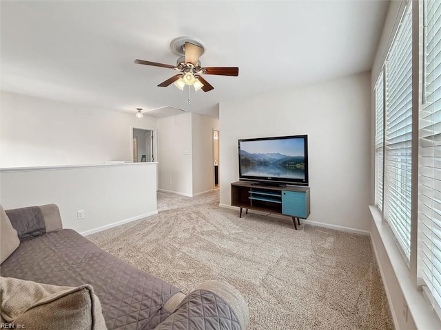 living room featuring baseboards, attic access, carpet, and a ceiling fan