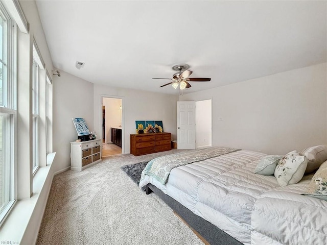 bedroom with carpet floors, ensuite bath, and a ceiling fan