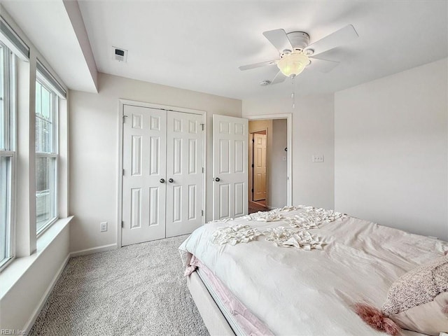 carpeted bedroom featuring baseboards, visible vents, a closet, and ceiling fan