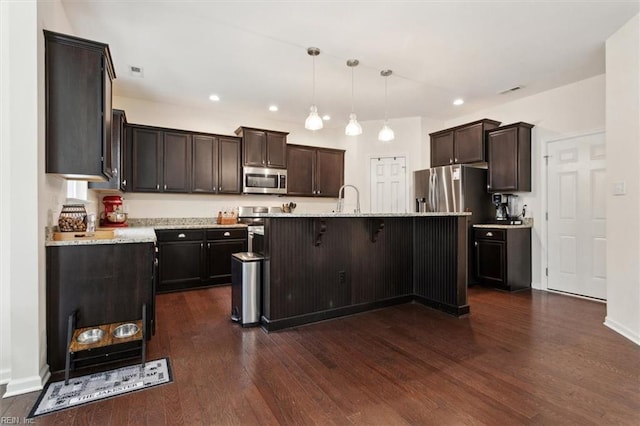 kitchen with a sink, dark brown cabinetry, dark wood-style floors, and stainless steel appliances