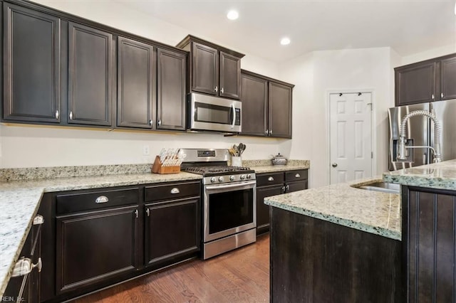 kitchen with light stone counters, recessed lighting, stainless steel appliances, dark brown cabinets, and dark wood-style flooring