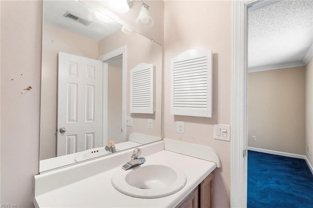 bathroom with vanity, baseboards, visible vents, a textured ceiling, and crown molding