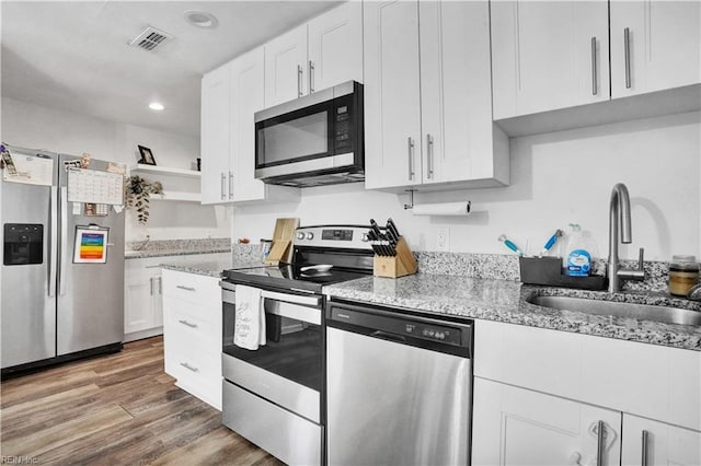 kitchen featuring visible vents, open shelves, a sink, stainless steel appliances, and white cabinetry