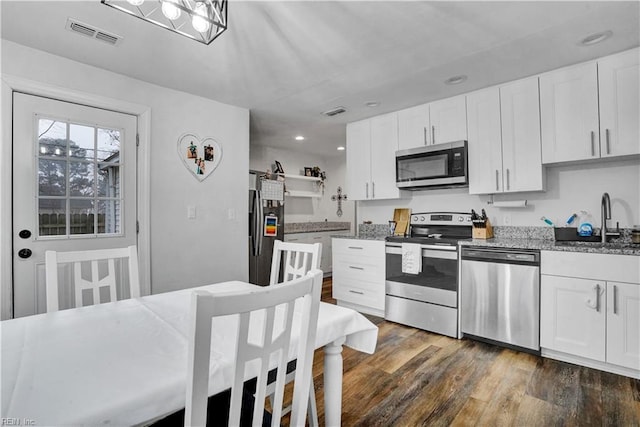 kitchen featuring visible vents, a sink, open shelves, stainless steel appliances, and dark wood-style flooring