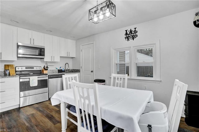 kitchen with a sink, stone countertops, dark wood-style floors, stainless steel appliances, and white cabinets