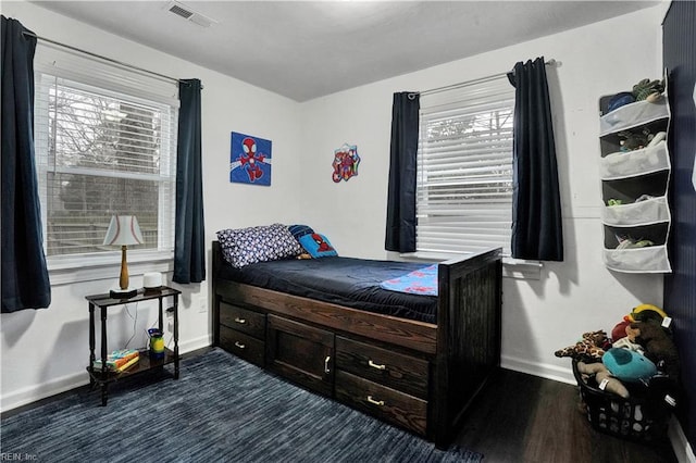 bedroom featuring dark wood finished floors, visible vents, and baseboards