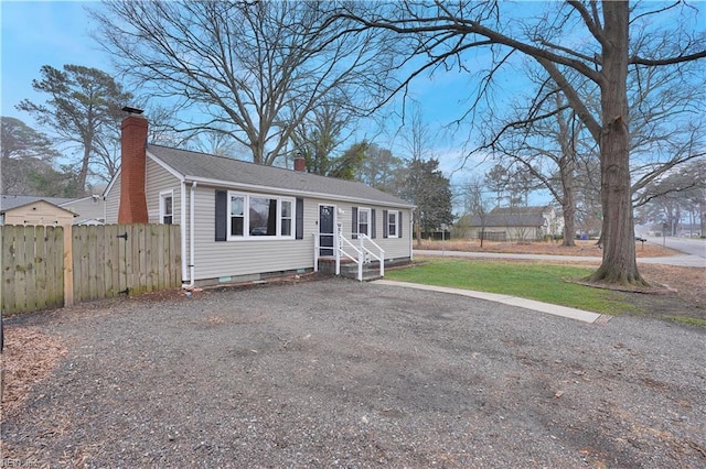 view of front of home featuring driveway, entry steps, fence, a front yard, and a chimney