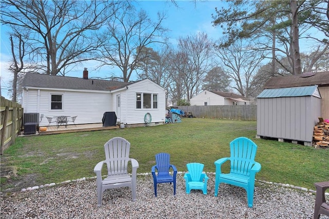 view of yard with a fire pit, a shed, a wooden deck, a fenced backyard, and an outdoor structure