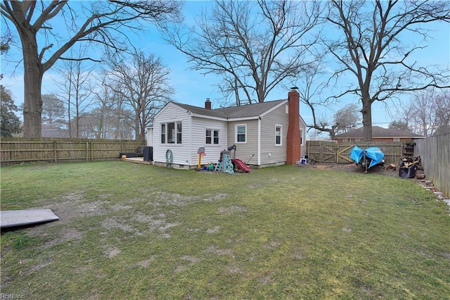 rear view of house featuring a lawn, a fenced backyard, and a chimney