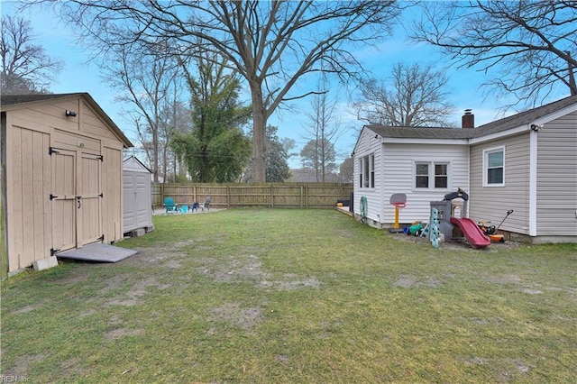 view of yard with an outbuilding, a fenced backyard, and a shed