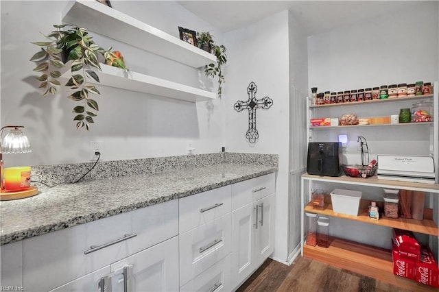 kitchen featuring open shelves, light stone counters, dark wood-style flooring, and white cabinetry