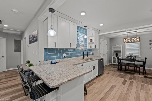 kitchen featuring light wood-type flooring, a sink, stainless steel dishwasher, backsplash, and white cabinets