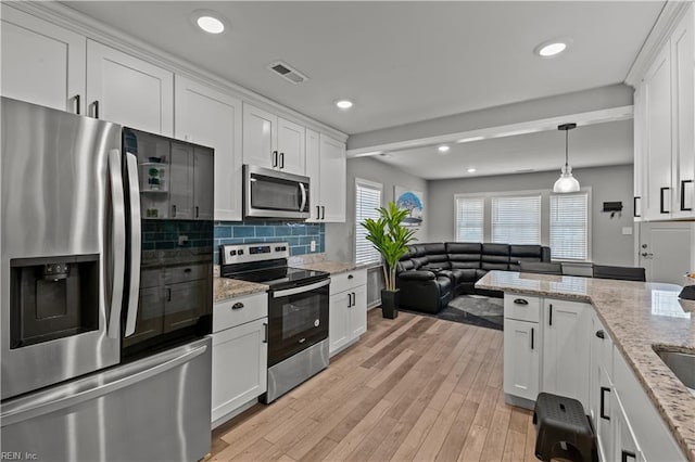 kitchen featuring white cabinetry, backsplash, light wood finished floors, and stainless steel appliances