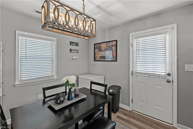 dining space with visible vents, baseboards, a notable chandelier, and wood finished floors