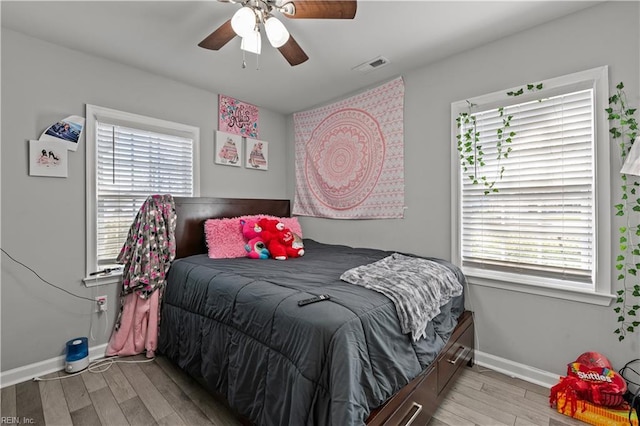 bedroom with ceiling fan, visible vents, baseboards, and light wood-style flooring