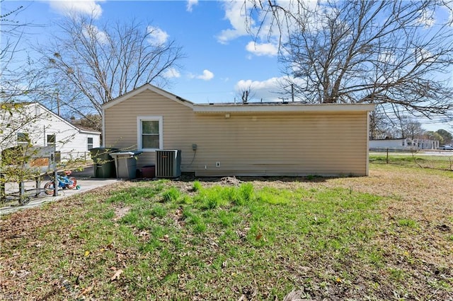 back of house with cooling unit, a lawn, and fence
