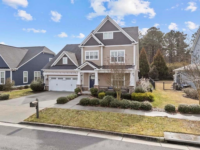 craftsman-style home featuring driveway, fence, covered porch, a front yard, and a garage