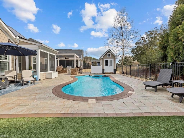 view of pool featuring an outbuilding, a patio, fence, an exterior structure, and a sunroom